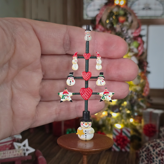 dollhouse miniature hand painted aren Markland snowman table top decor, signed. in focus in front of a hand