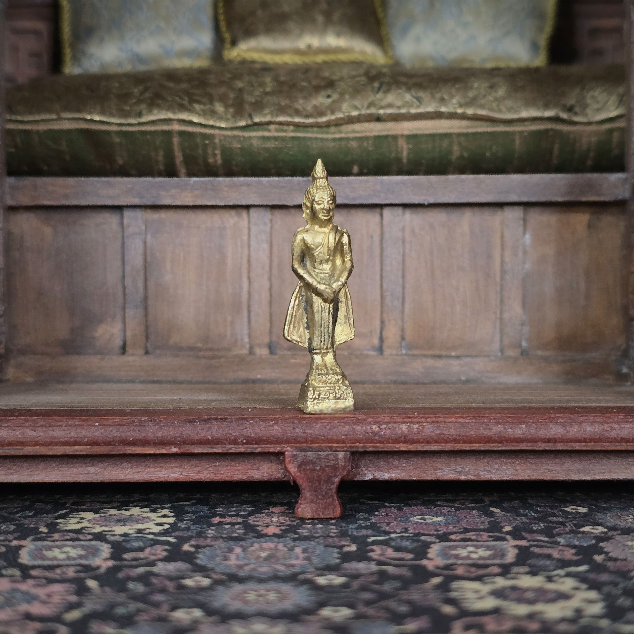 Gold statue on a wooden platform with a patterned rug below
