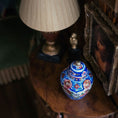 Load image into Gallery viewer, Decorative vase with floral patterns on a wooden surface next to a lamp and framed picture.
