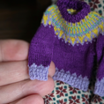 Load image into Gallery viewer, Close up detail of stitches on a Dollhouse miniature hand-knitted sweater with a colorful pattern held by a hand against a blurred background
