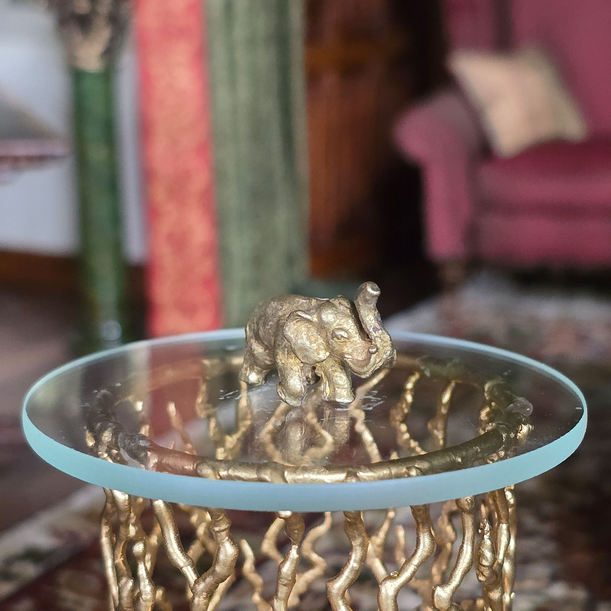 Gold elephant figurine on a glass table with a blurred indoor background
