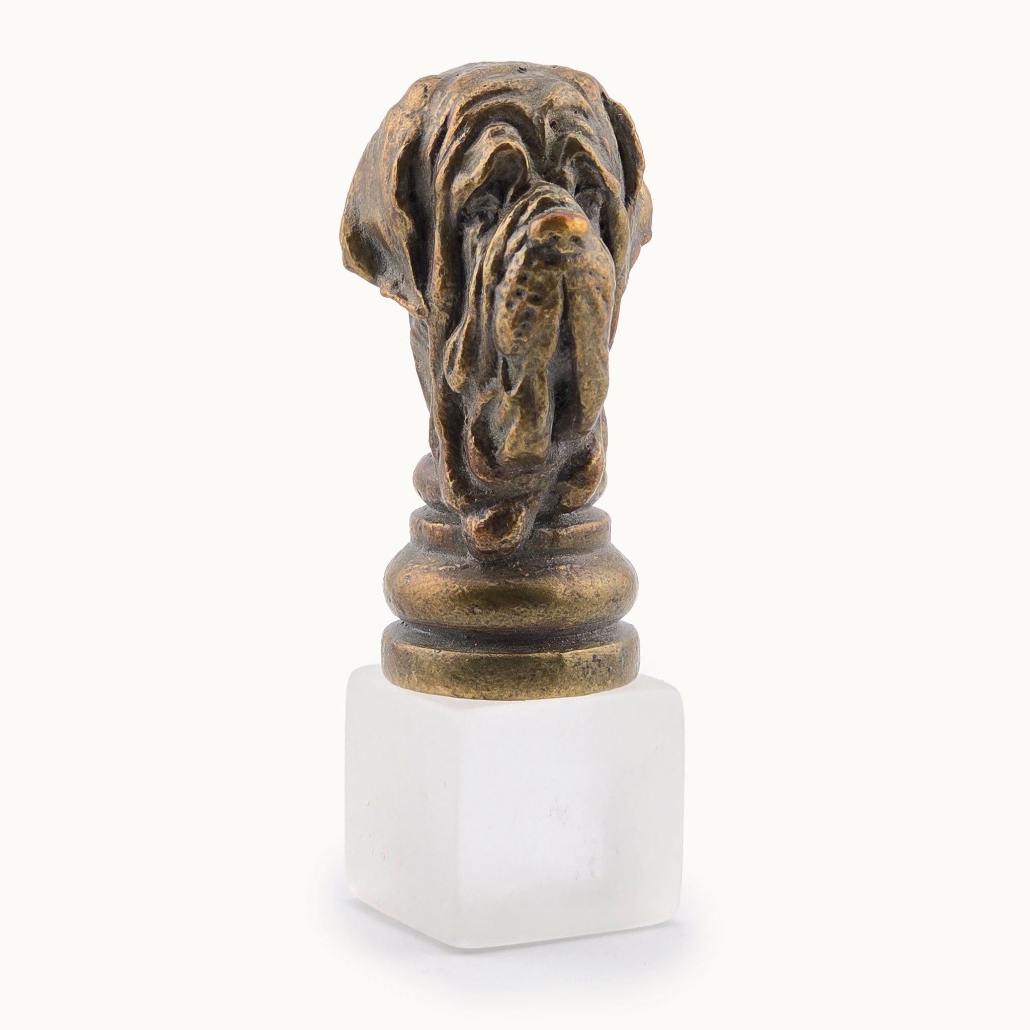 Decorative metal miniature bronze-colored dog sculpture on a white base