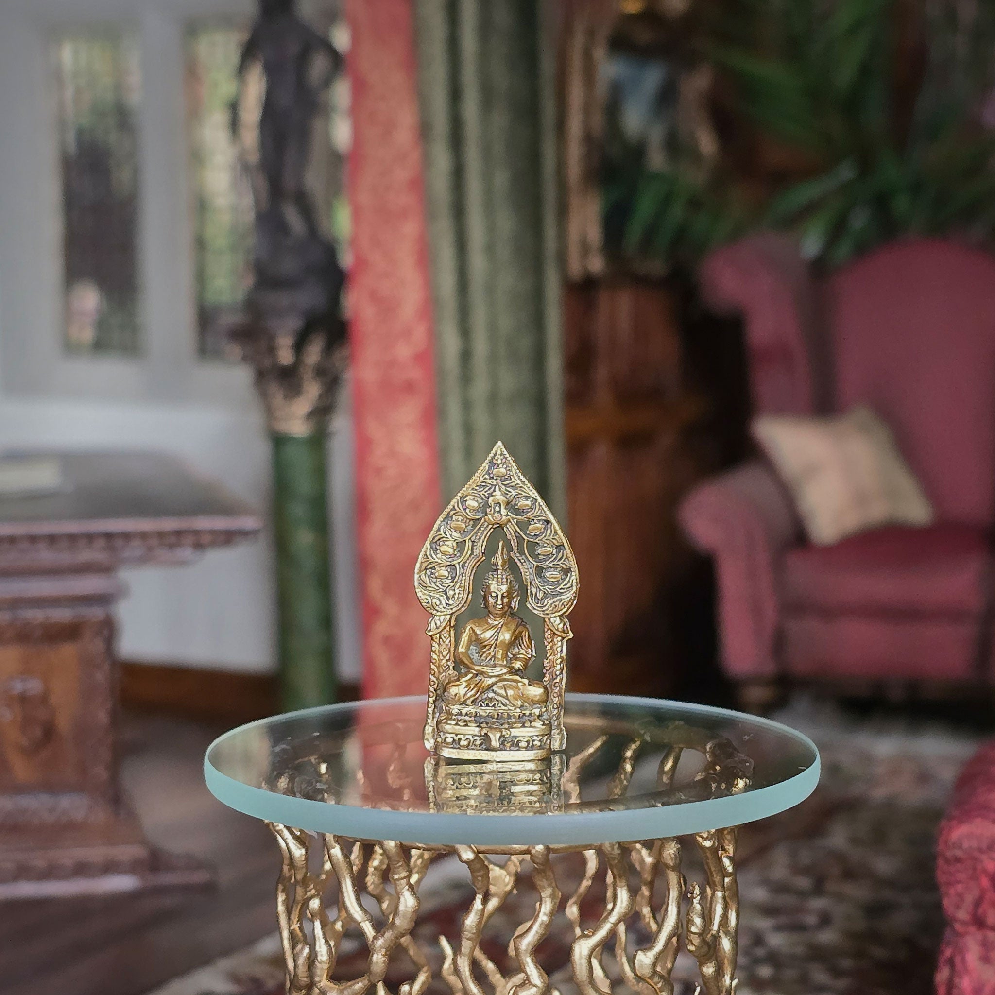 Decorative gold statue on a glass table with a blurred indoor setting
