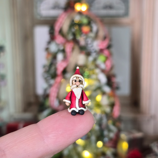 Miniature Folk Art Santa Figurine – Hand-Sculpted Clay, balanced on a figure in a festive room