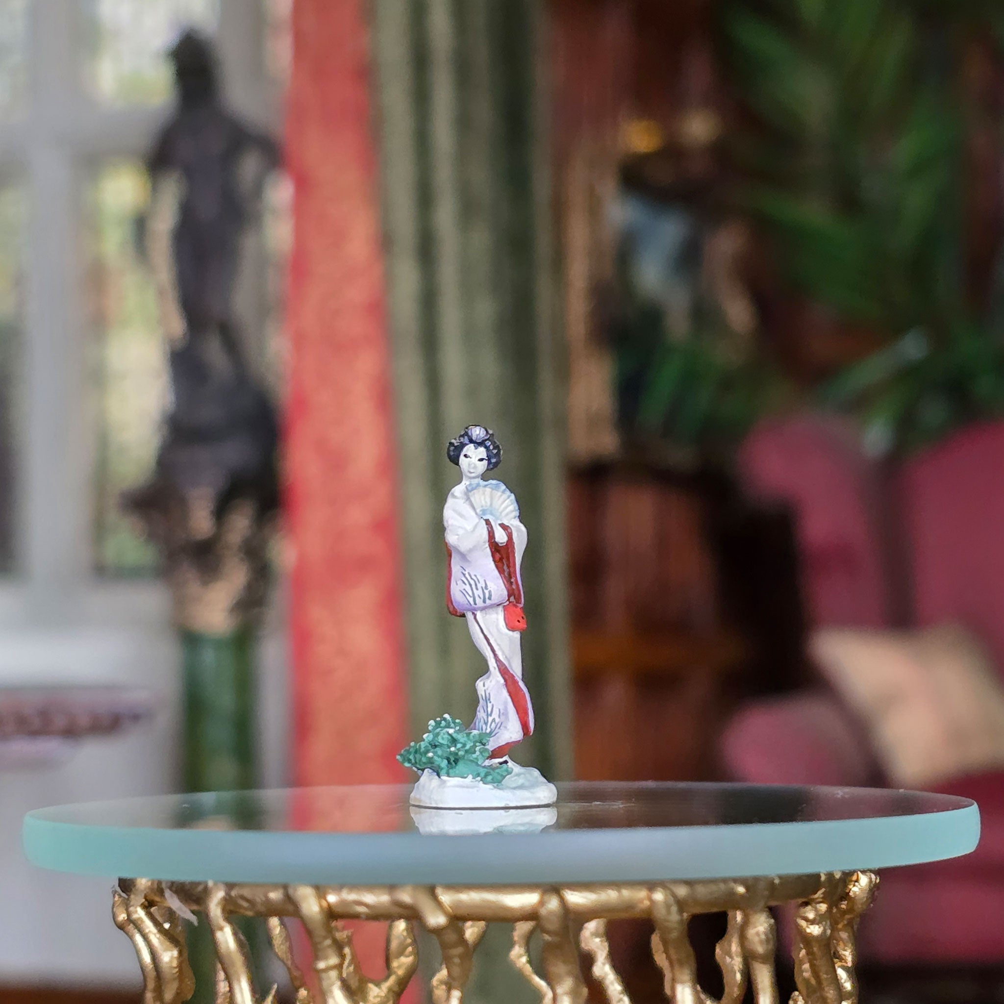 Small figurine on a glass table with a blurred indoor background