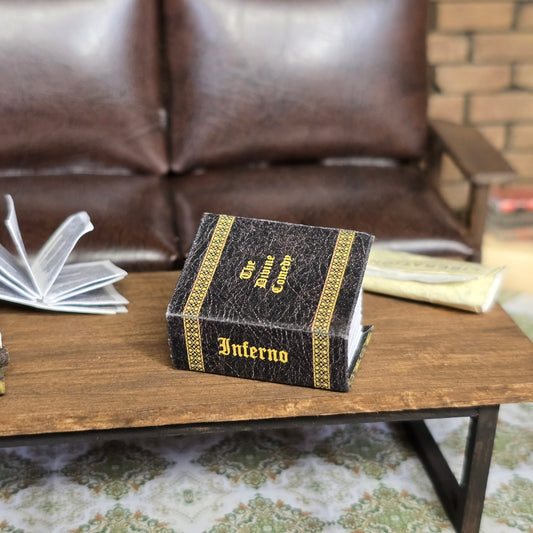 Decorative book titled 'Inferno' on a wooden table with a blurred sofa and rug in the background