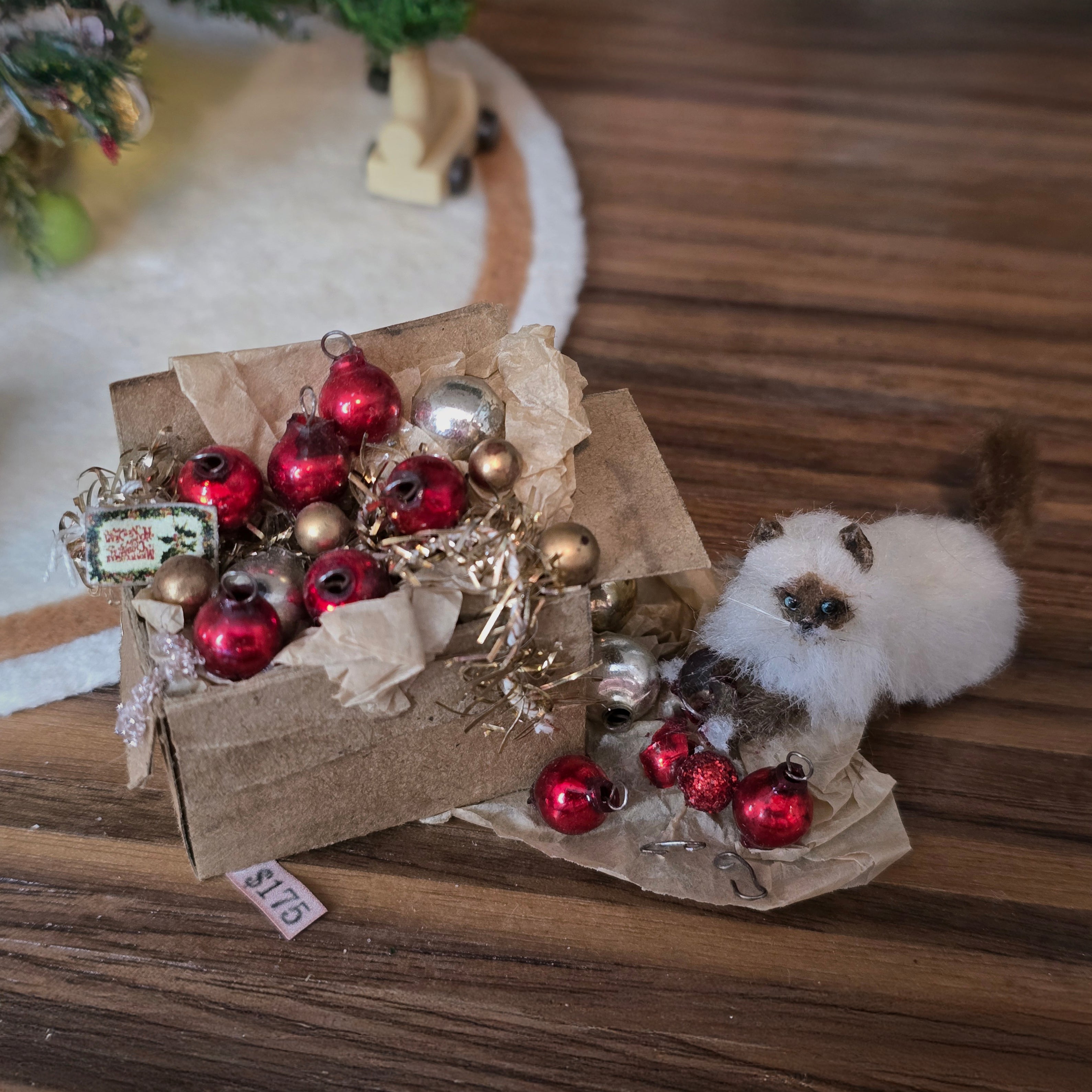 Small box with red and gold ornaments and a small white dog with a brown patch on a wooden surface.