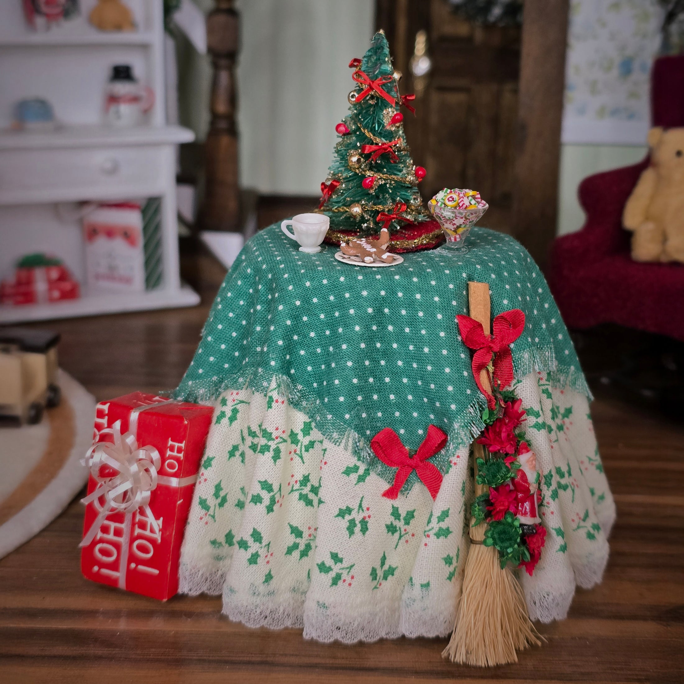 Decorative Christmas scene with a small table, tree, and gift box on a wooden floor.