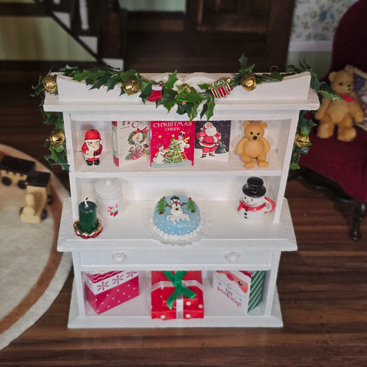 Decorative white shelf with Christmas-themed items including cards, teddy bears, and small figurines.