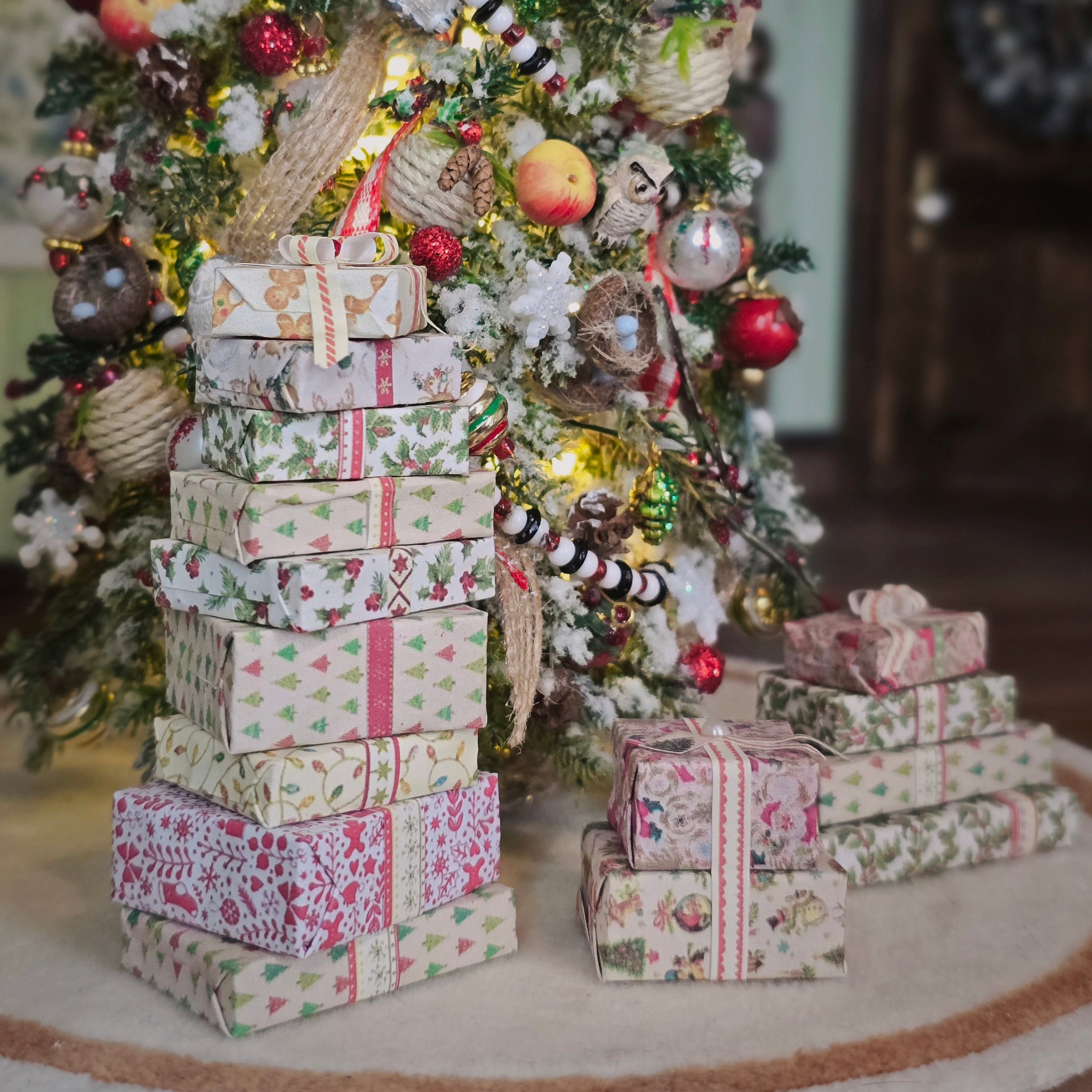 Stack of decorative Christmas presents in front of a decorated tree.