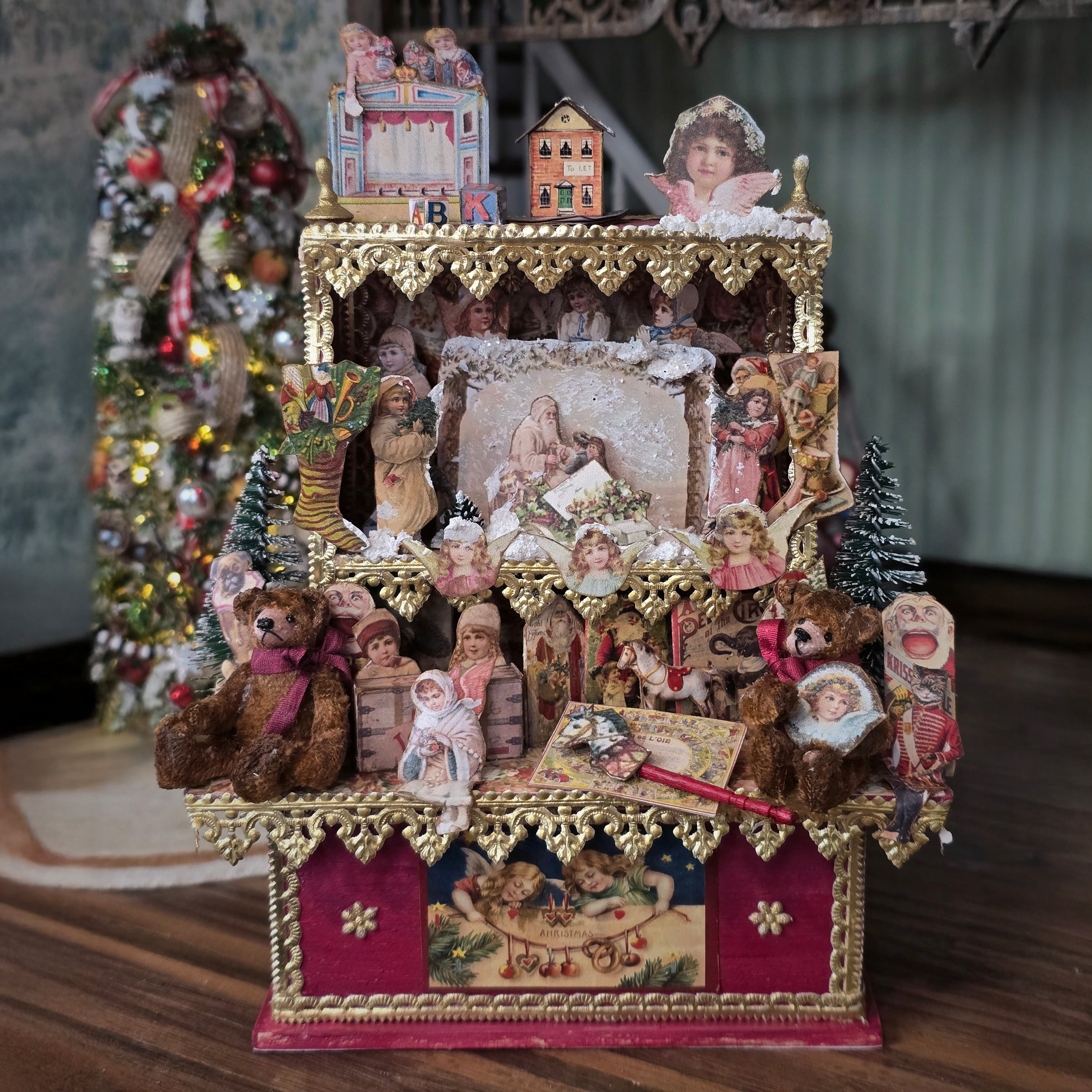 Decorative Christmas scene with figurines, teddy bears, and a small tree on a wooden surface.