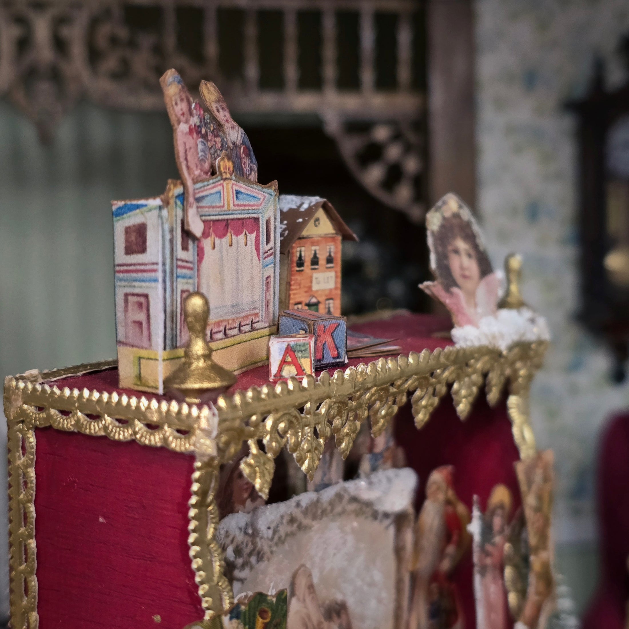 Decorative miniature scene with a gold frame, red fabric, and vintage-style elements.