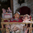 Load image into Gallery viewer, Vintage-style diorama with small figures and buildings on a decorative stand.
