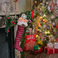 Load image into Gallery viewer, Christmas stocking hanging by a fireplace with a decorated tree in the background

