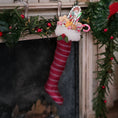 Load image into Gallery viewer, Red striped Christmas stocking with candy canes and and toys hanging on a fireplace mantel.
