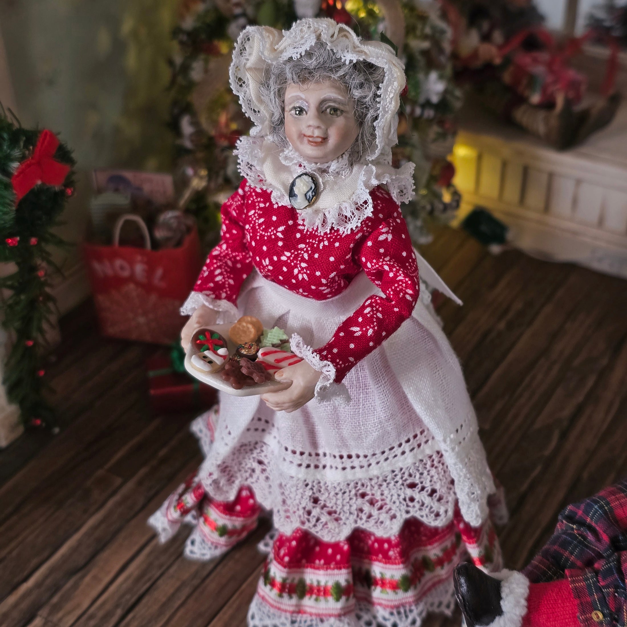 Mrs. Claus miniature doll in a festive setting with Christmas decorations in the background
