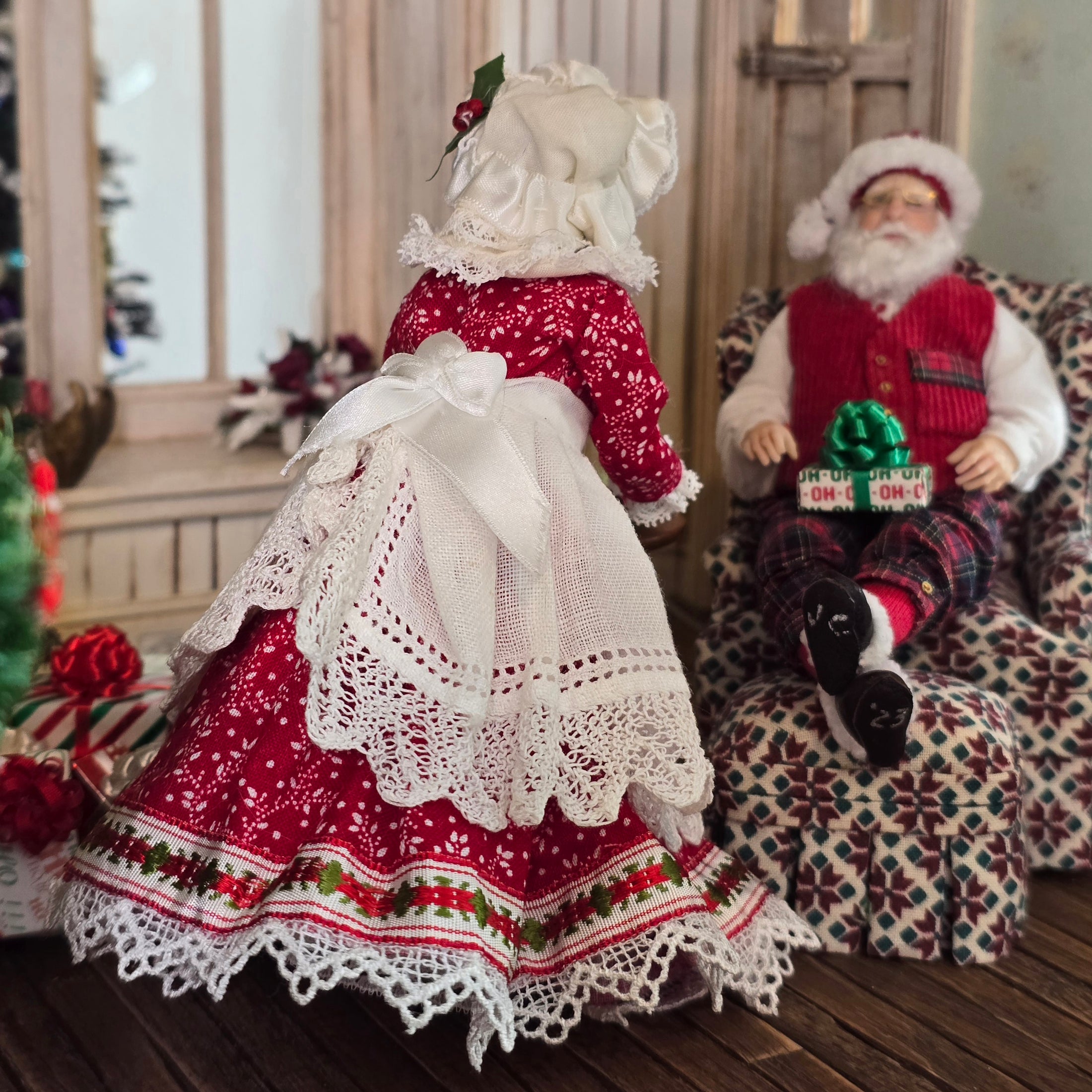 Mrs. Claus miniature doll with Santa Claus sitting on a patterned chair.