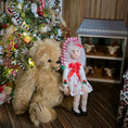 Load image into Gallery viewer, Large teddy bear and  Christmas girl doll by artisan Carol McBride in front of a decorated Christmas tree with a dollhouse in the background.
