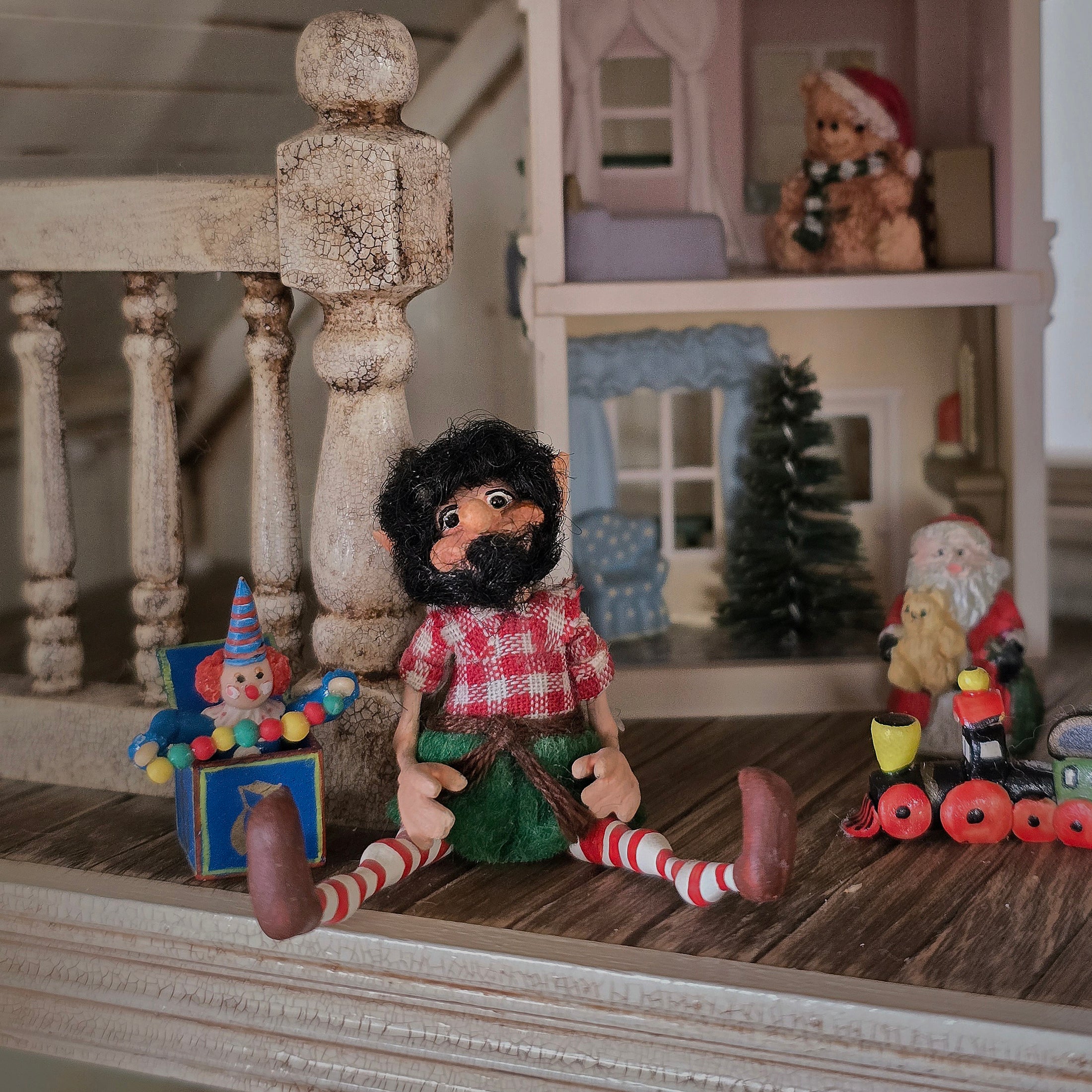 black-bearded elf dollhouse doll in a checkered shirt surrounded by toys
