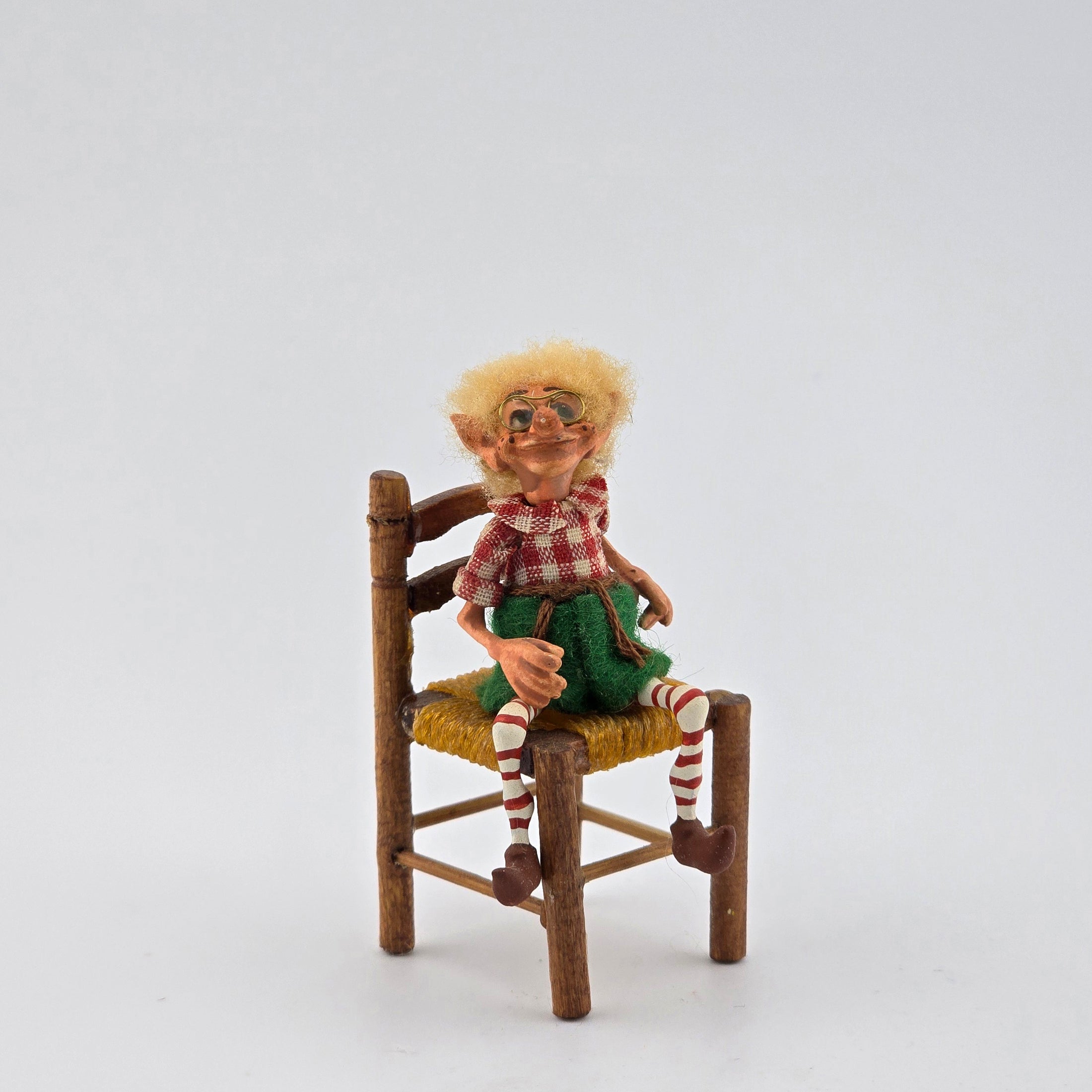 Christmas elf with glasses by artist Cynthia Baron, in chair on white background