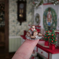 Load image into Gallery viewer, Miniature chocolate roll cake with a snowman on a decorative plate held in front of a festive background.
