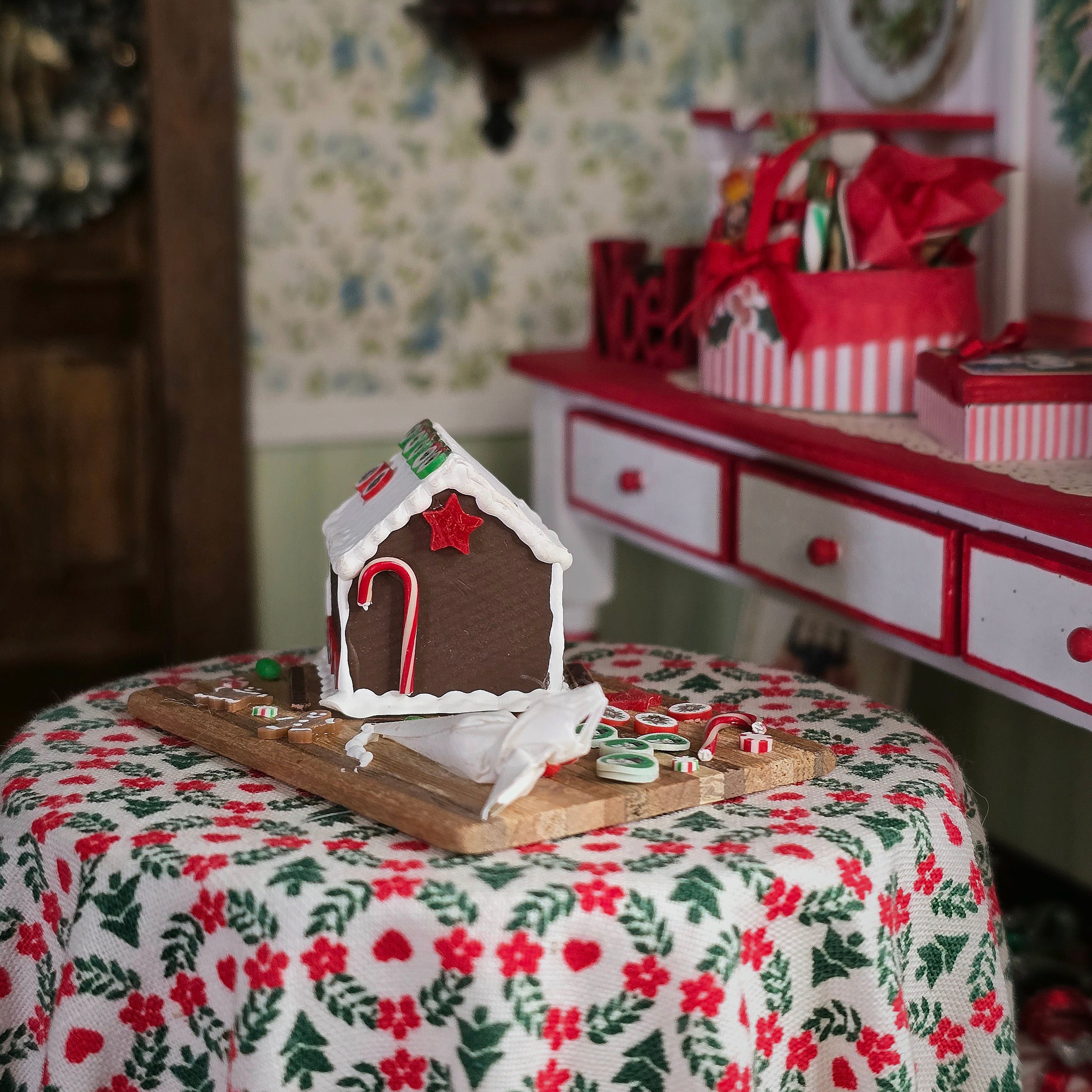 Gingerbread house on a table with a festive tablecloth and decorative background
