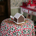 Load image into Gallery viewer, Gingerbread house on a floral tablecloth with a blurred background
