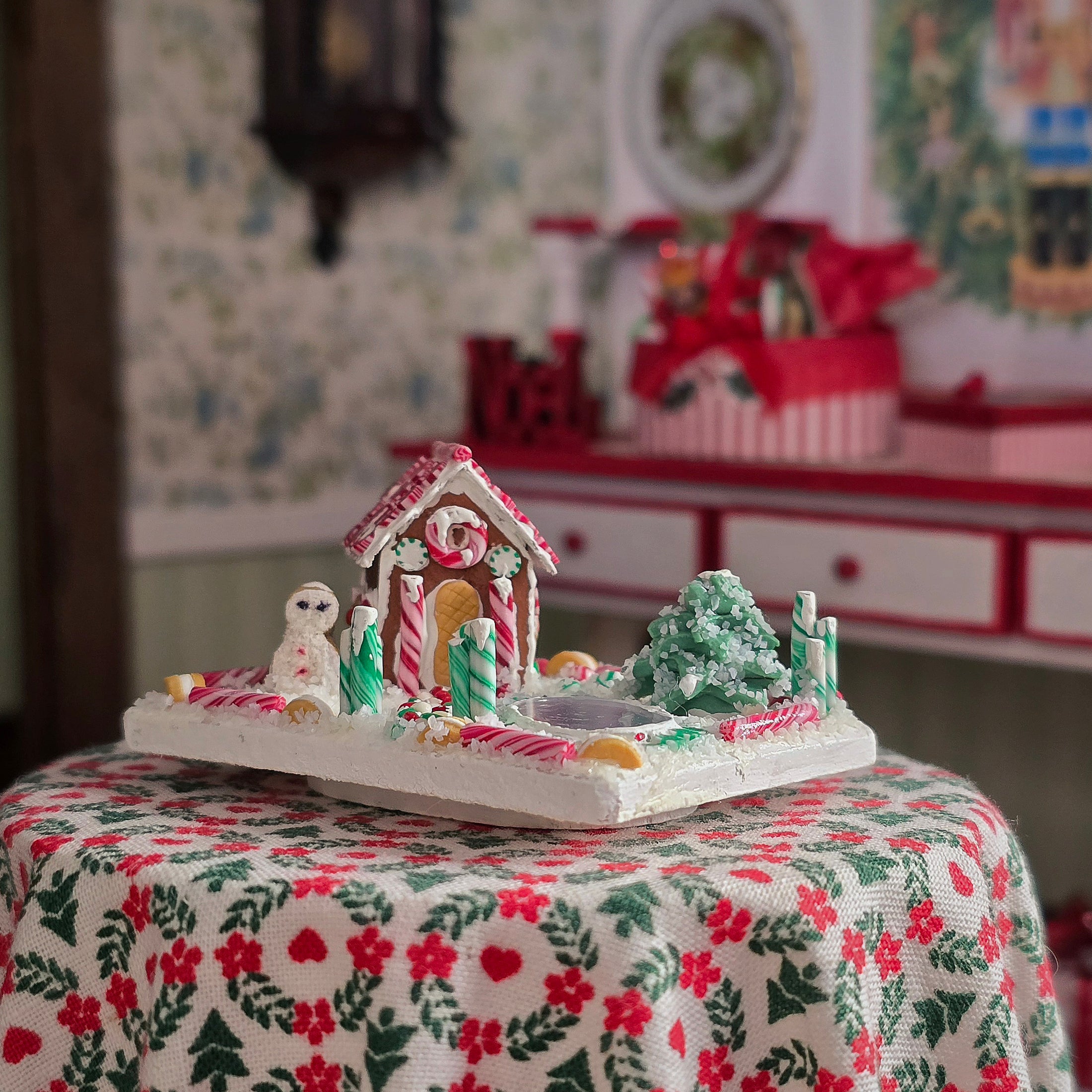 Gingerbread house with candy decorations on a floral tablecloth