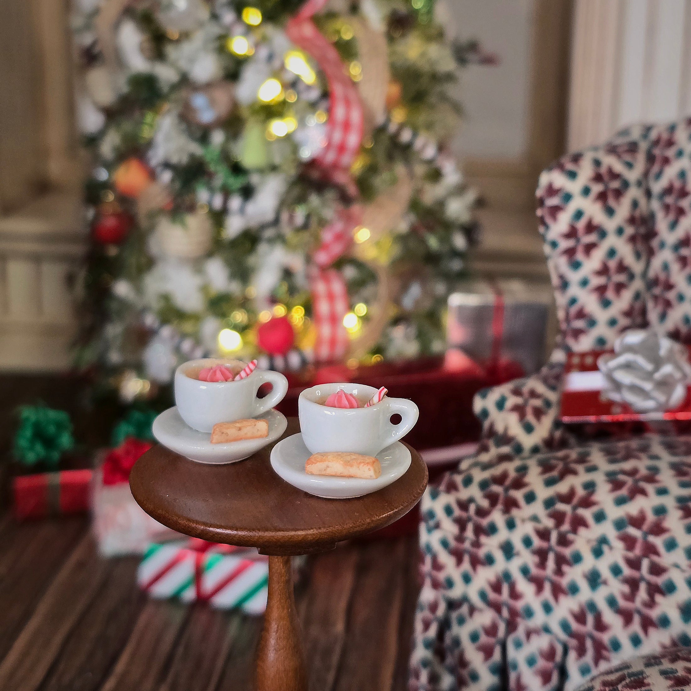 Pair of miniature hot cocoa cups with cream and biscotti in festive room, on table