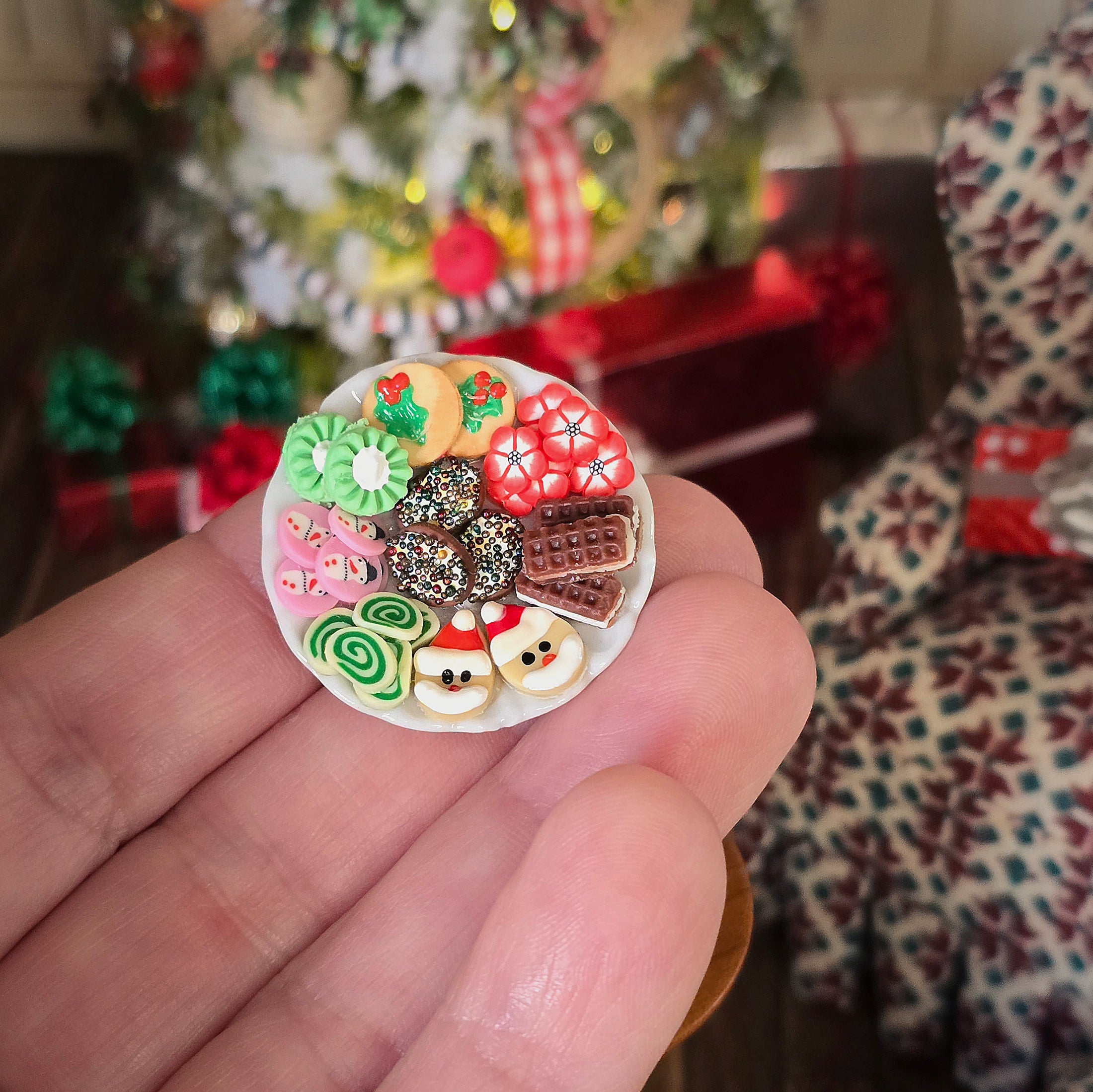 Miniature dollhouse cookie platter, held in a hand with a festive background.