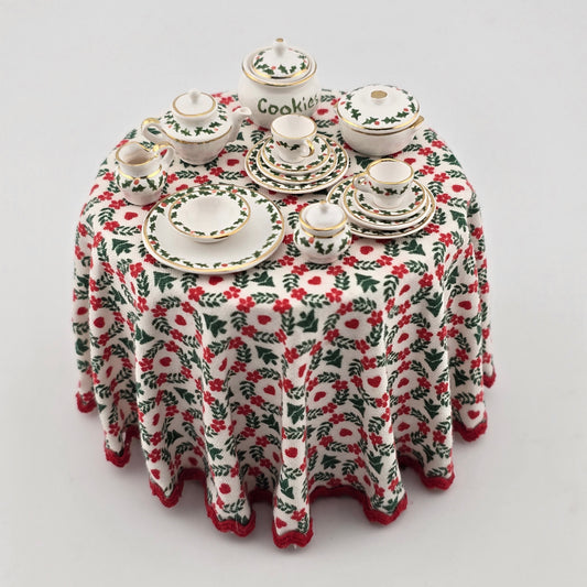 Miniature Christmas-themed table setting with a patterned tablecloth on a white background