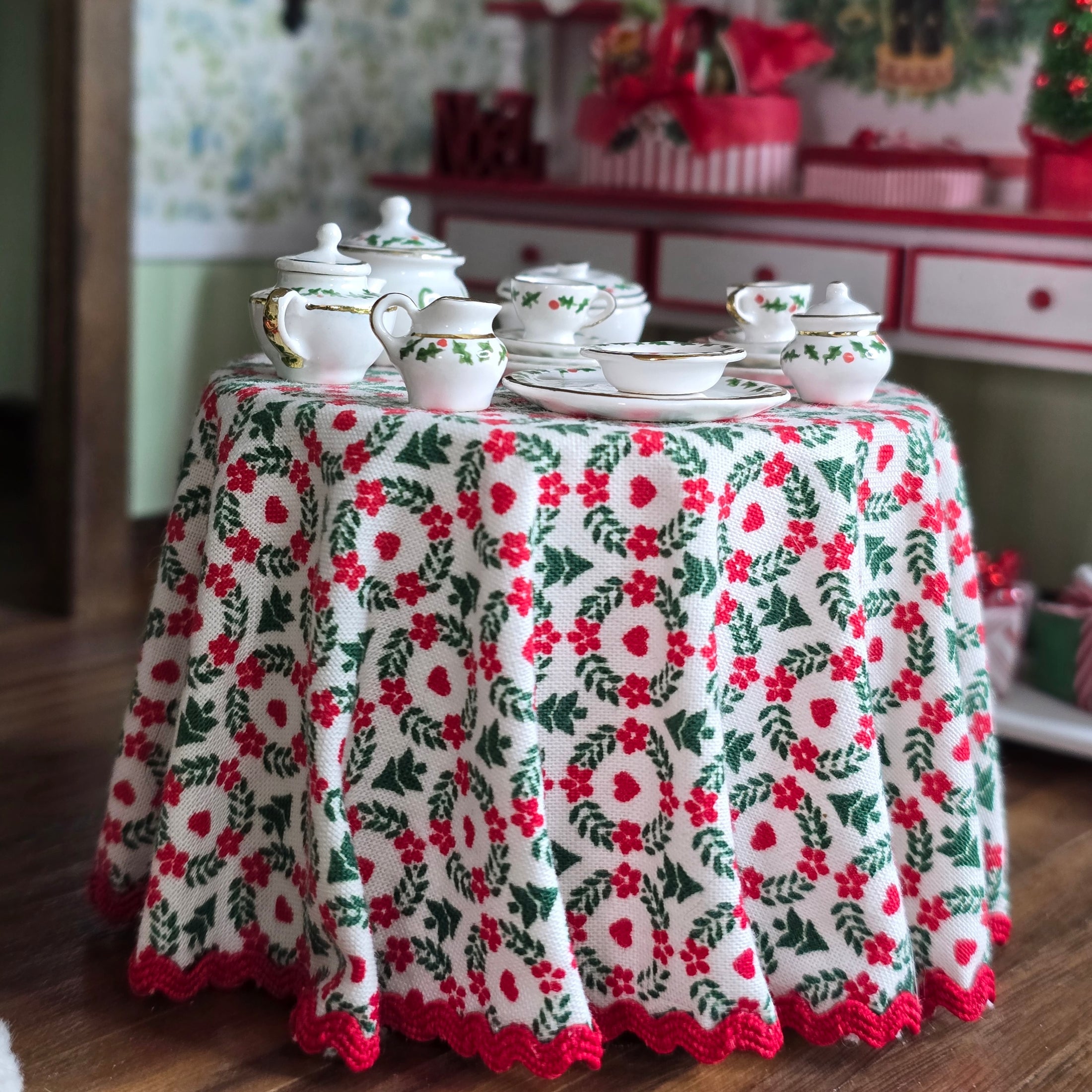 Round table with a floral tablecloth and teacup set in a room with holiday furniture and decor.