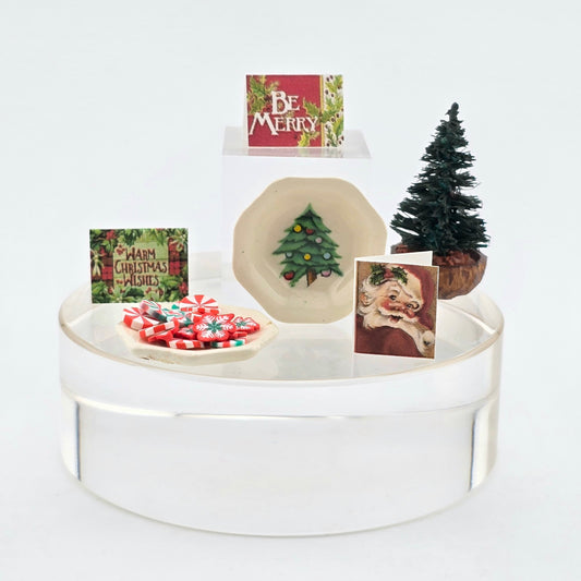 Christmas-themed display with cookies, cards, and a small tree on a white stand.