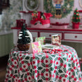 Load image into Gallery viewer, Decorative table setting with a floral tablecloth, small Christmas tree, and cards in a festive room.
