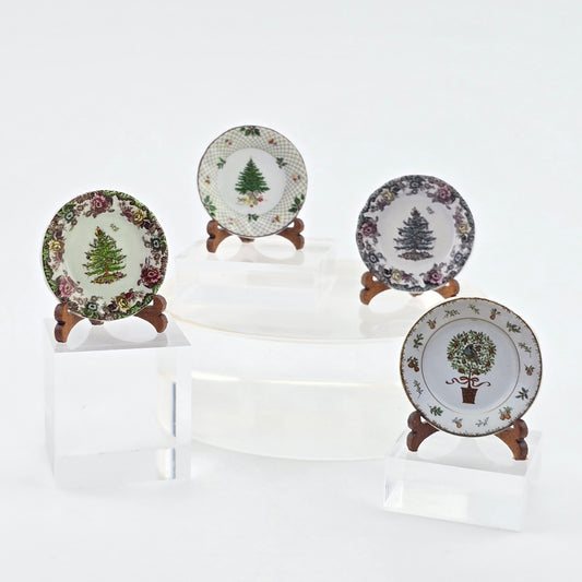 Four decorative plates with tree designs on stands against a white background