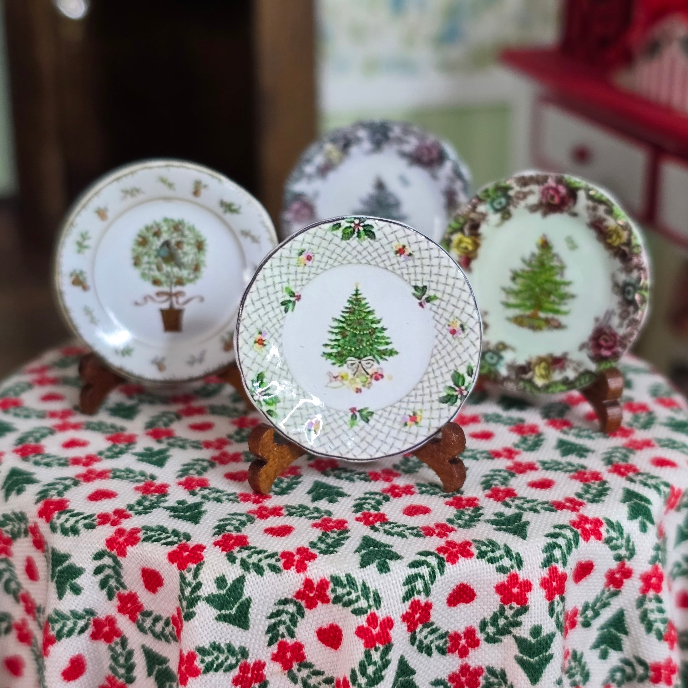 Decorative plates with Christmas tree designs on a floral tablecloth.