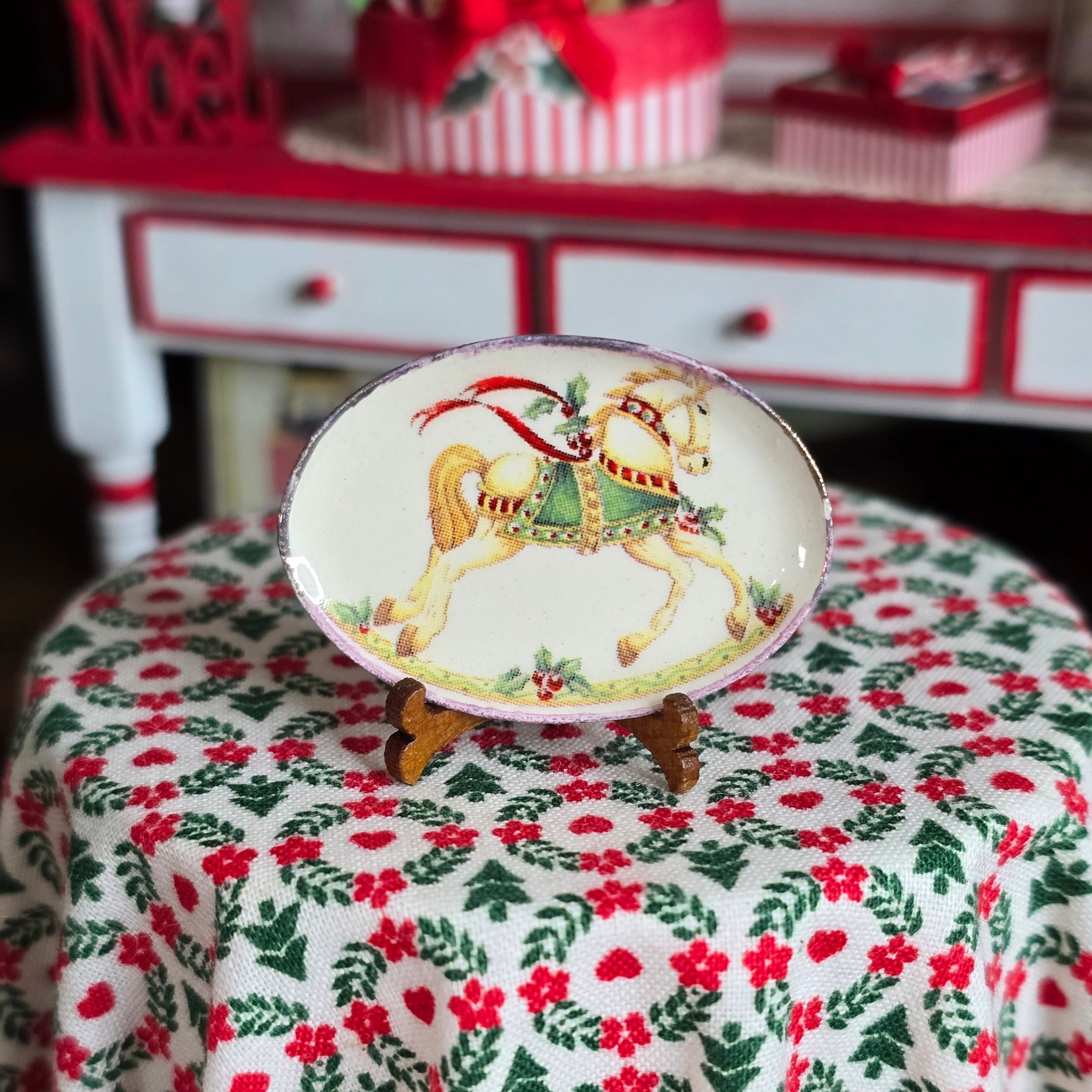 Decorative dollhouse plate with a rocking horse design on a tablecloth with floral pattern