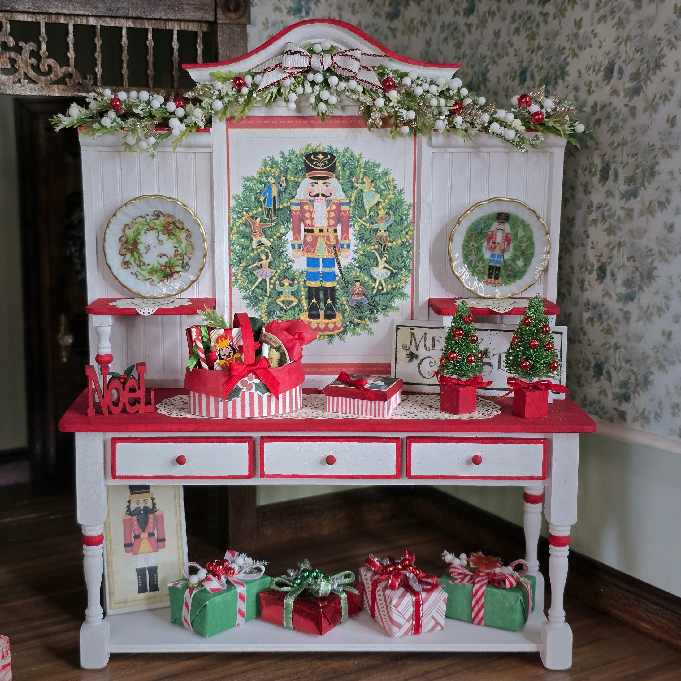 Decorative Christmas shelf with a Nutcracker theme, including plates, figurines, and gift boxes.