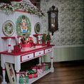 Load image into Gallery viewer, Decorative Christmas setup with a red and white table, nutcracker, and floral wallpaper.
