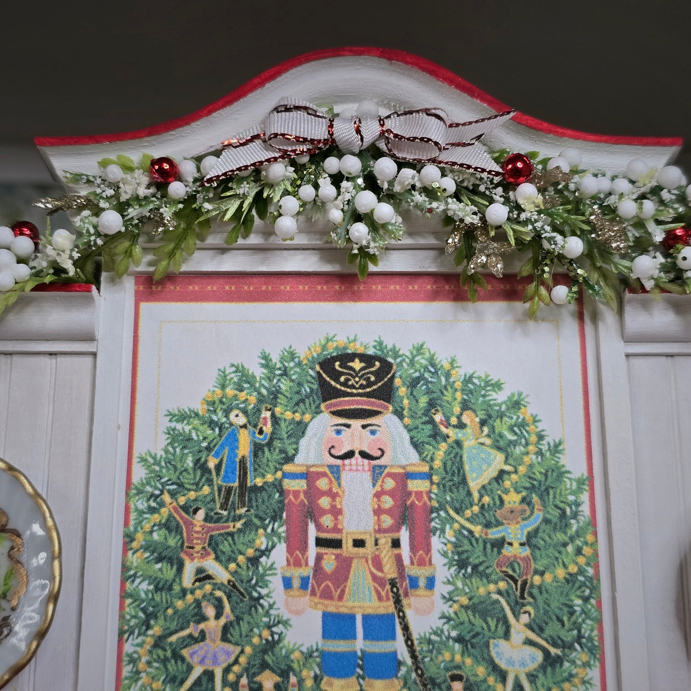 Decorative wall piece with a nutcracker design and Christmas garland above it.