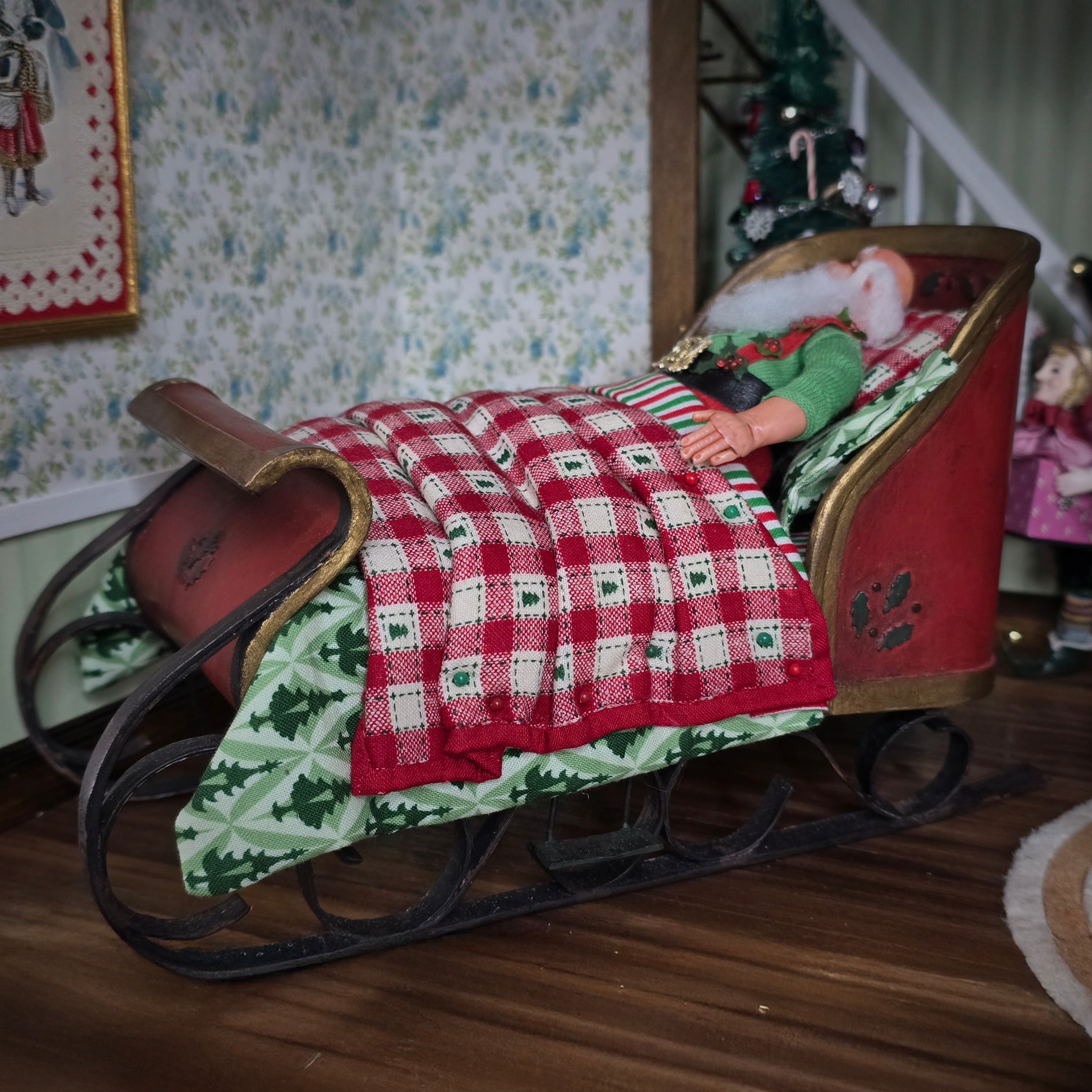 Sleigh bed with a Santa doll lying under a checkered blanket in a festive setting