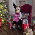 Load image into Gallery viewer, Elf boy doll carrying jack-in-the-box toy in a festive setting with a Christmas tree and presents.
