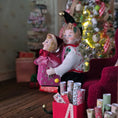 Load image into Gallery viewer, Elf boy doll carrying jack-in-the-box toy with a Christmas tree and presents in the background
