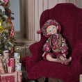 Load image into Gallery viewer, Hand-Sculpted Clay Elf Boy in Raspberry Pinkl in a floral outfit sitting on a red chair with Christmas decorations in the background.
