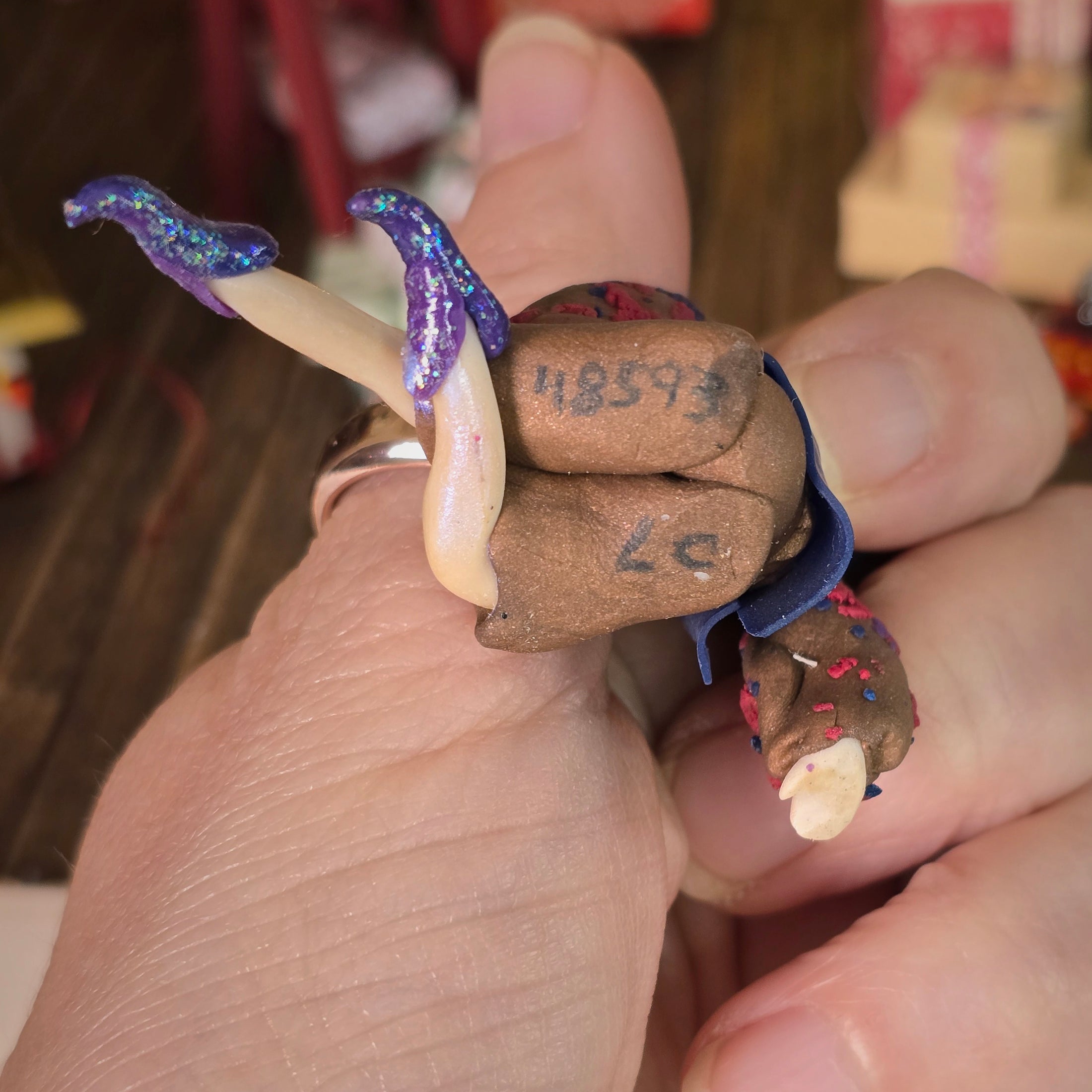 singed underside of Sculpted clay elf boy doll wearing a purple outfit