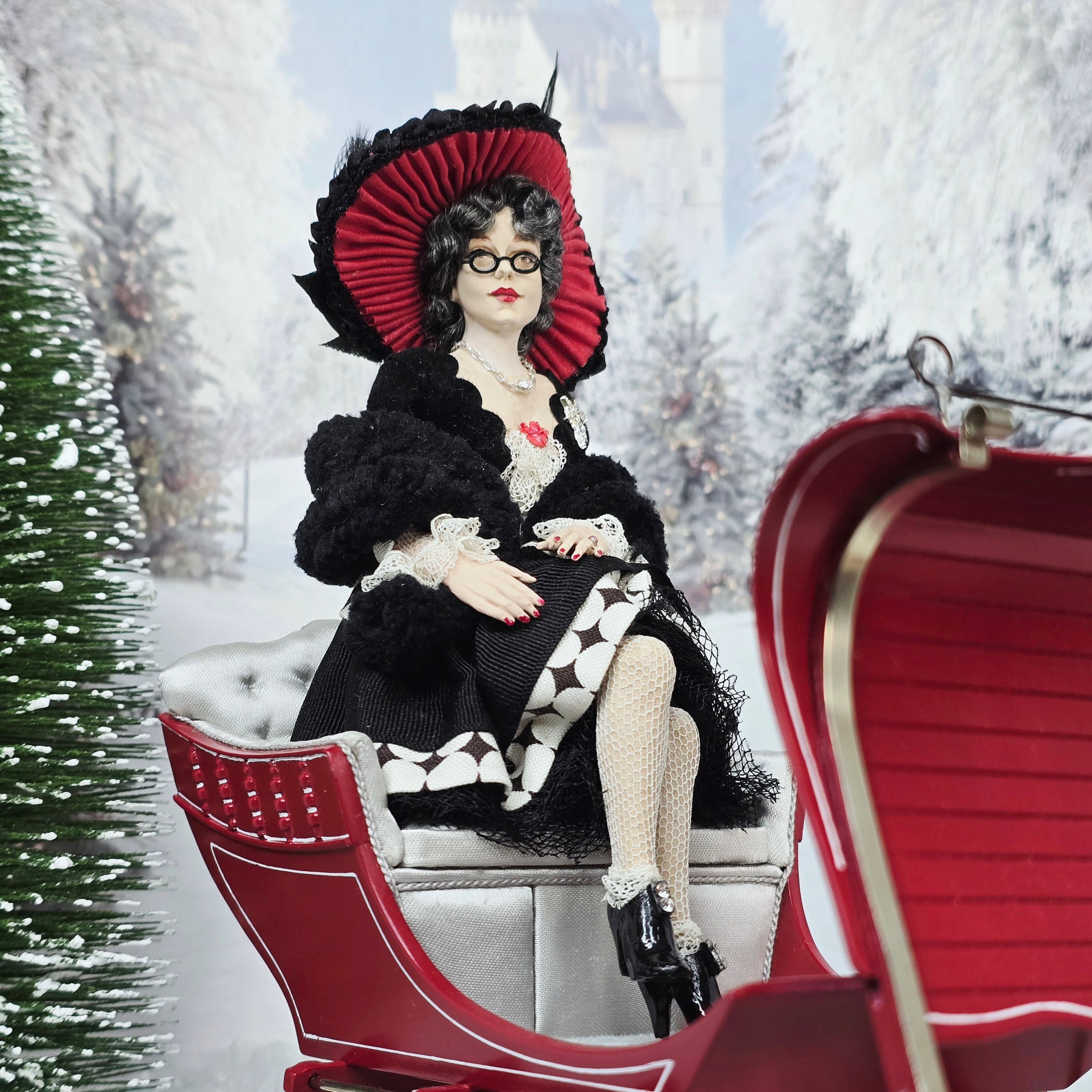 “Winter Lady” Doll in a winter scene with a red sleigh and snow-covered trees.