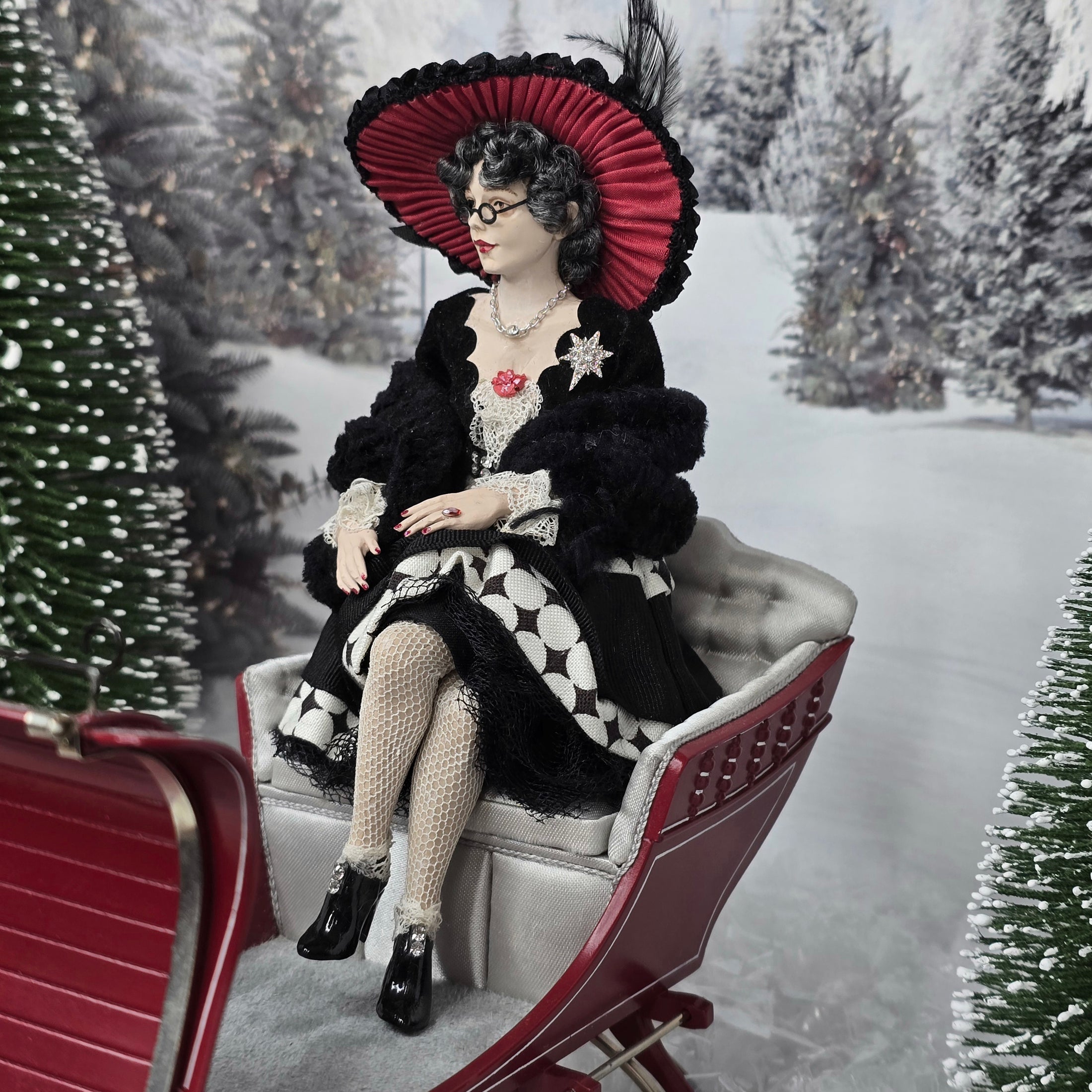“Winter Lady” Doll in vintage attire sitting on a sleigh in a snowy landscape