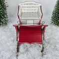 Load image into Gallery viewer, Red sleigh with white seat on a snowy background
