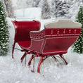 Load image into Gallery viewer, Red sleigh with white seats in a snowy landscape, rear view
