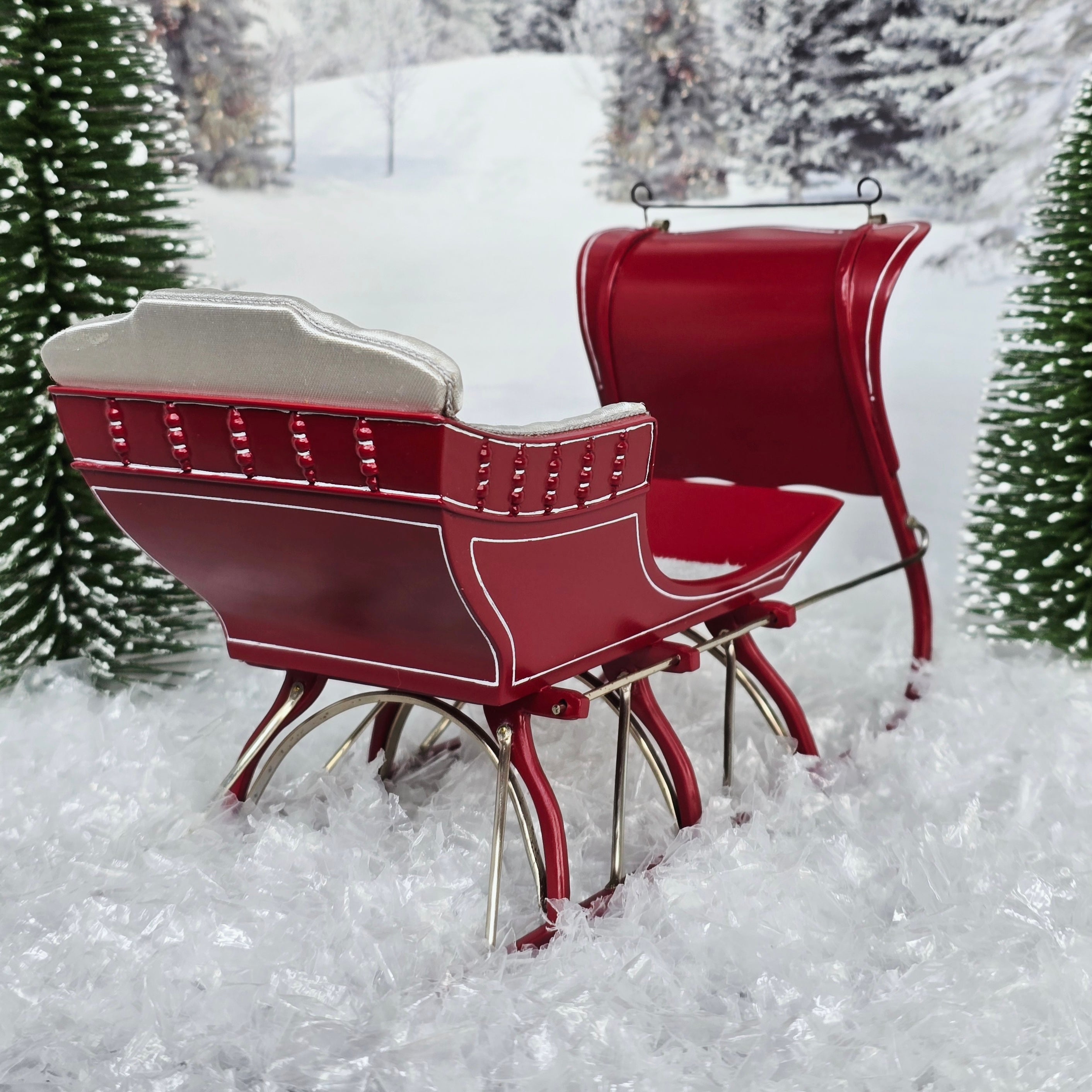 Red sleigh in a snowy landscape with Christmas trees.